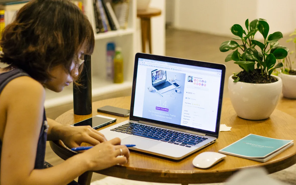Person planning work with a notebook beside a laptop