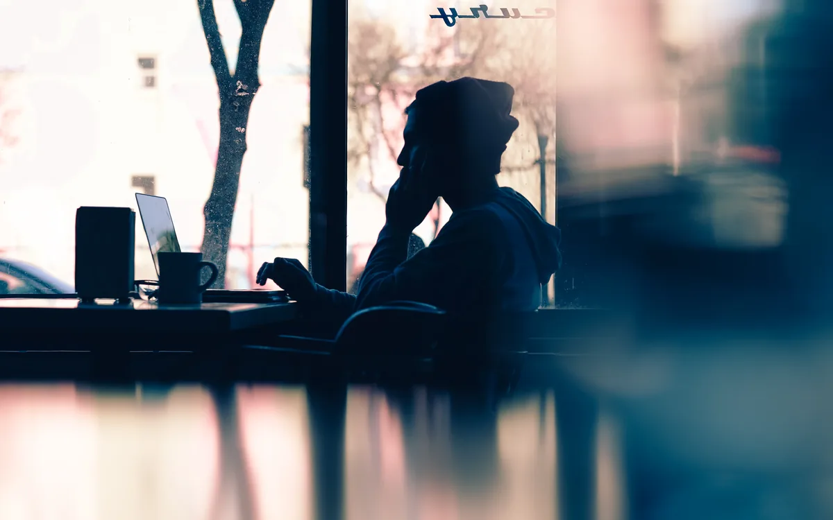 Person working on a laptop in a cafe, focused on growing their business
