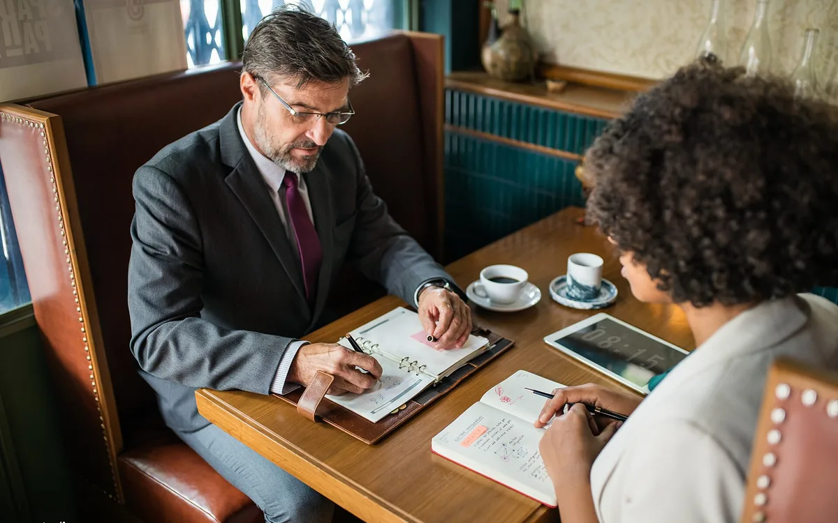 Two people at a table talking through a process with notes