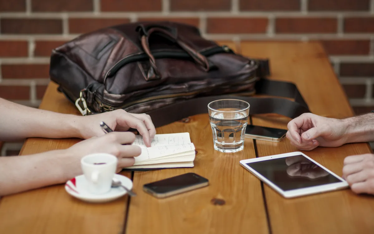 Two people in a friendly check-in meeting with phones and a tablet